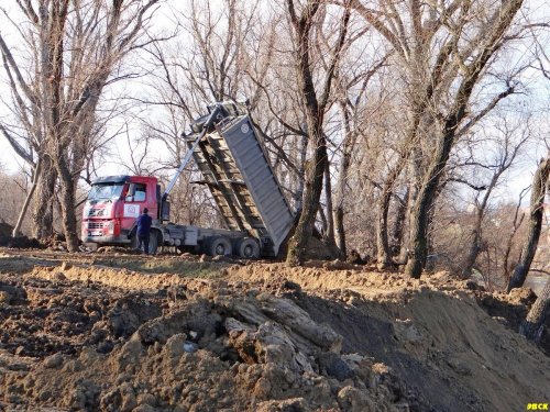 Грузовой автомобиль высыпает землю в старицу реки 